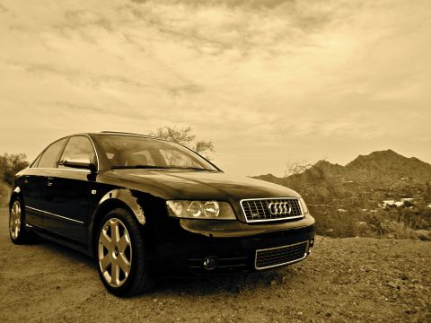 2005 Audi S4 - A black 2005 Audi S4 sedan is captured from a three-quarter front view, parked on a dirt road with a mountainous landscape behind it.