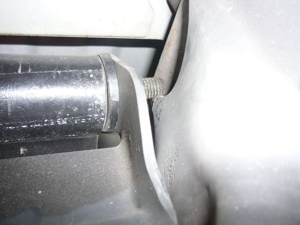 Close-up of threaded stud in a stamped steel mounting bracket beside black plastic housing