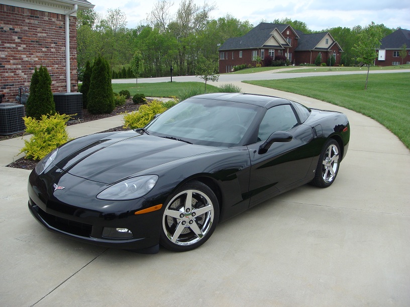 Black 2006 Chevrolet Corvette parked on a concrete driveway in front of a brick house