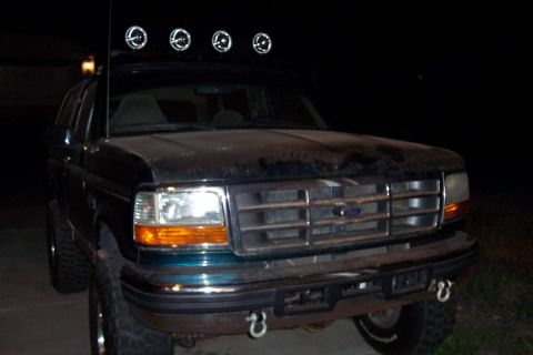 1995 Ford Bronco - Front view of a dark green Ford Bronco with a light bar mounted on the roof.