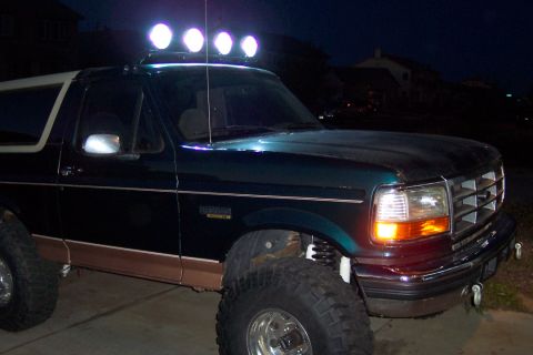 1995 Ford Bronco - A dark green Ford Bronco with a light bar is parked at night.