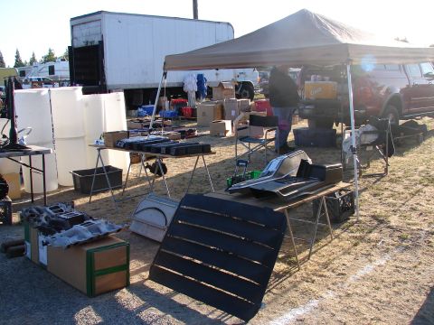 1973 Ford Ranchero - Various car parts, including interior trim, are laid out on tables at an outdoor market stall.
