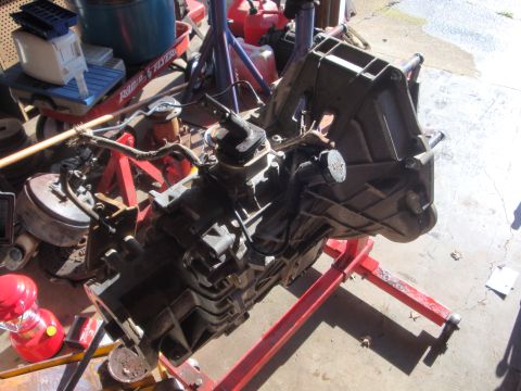 1989 Ford Bronco - A transmission assembly is mounted on a red engine stand, suggesting it is either being installed or removed from a vehicle.