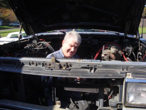 1989 Ford Bronco - Mechanic works on the engine of a 1989 Ford Bronco with the hood up.