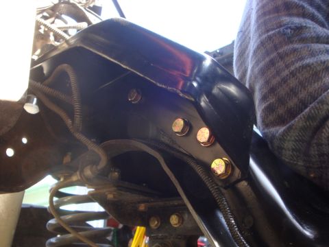 1989 Ford Bronco - Bolts secure the frame and suspension components of a vehicle, showing part of the engine bay.