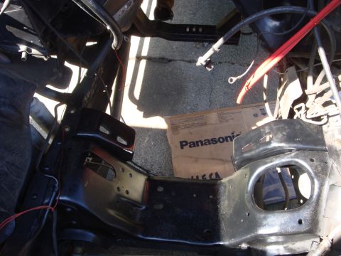 1989 Ford Bronco - A view of a vehicle's engine bay frame, with some wiring visible and a cardboard box on the ground.