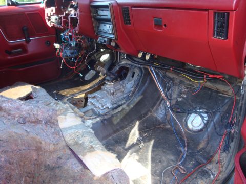 1989 Ford Bronco - The interior of a vehicle is shown with the floor carpeting removed and extensive wiring exposed, indicating ongoing work.