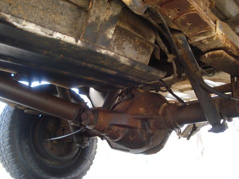 1989 Ford F-250 - The underside of a truck shows significant rust on the rear axle and drivetrain components.