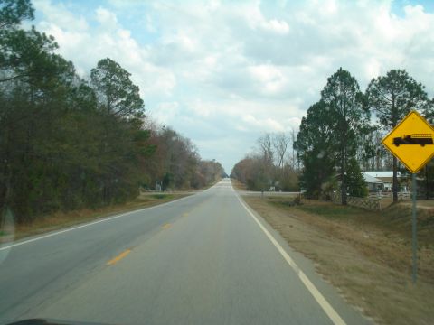 1989 Ford F-250 - A yellow diamond warning sign depicting a fire truck is visible on the right side of a two-lane road.