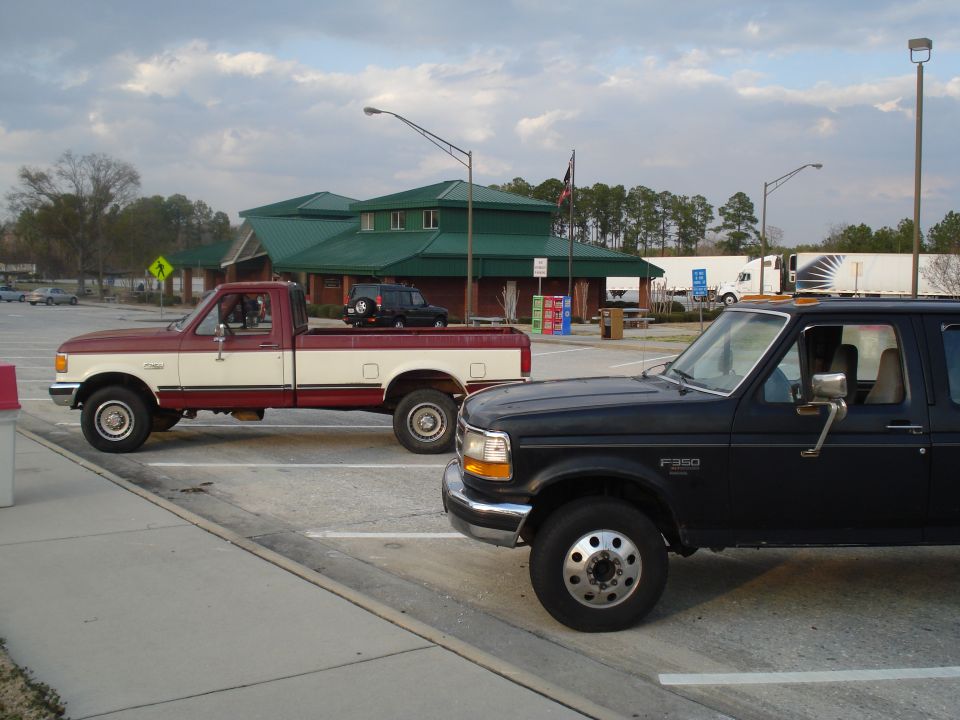 1989 Ford F-250 crew cab pickup truck, black, 3q-front view. Another red and white pickup is parked behind