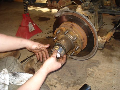 1989 Ford F-250 - A mechanic is shown working on a vehicle's wheel hub assembly, likely during a repair or maintenance procedure.