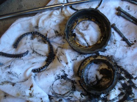 1989 Ford F-250 - Worn drivetrain components, including a fractured metal ring and greasy housings, are laid out on a white cloth.