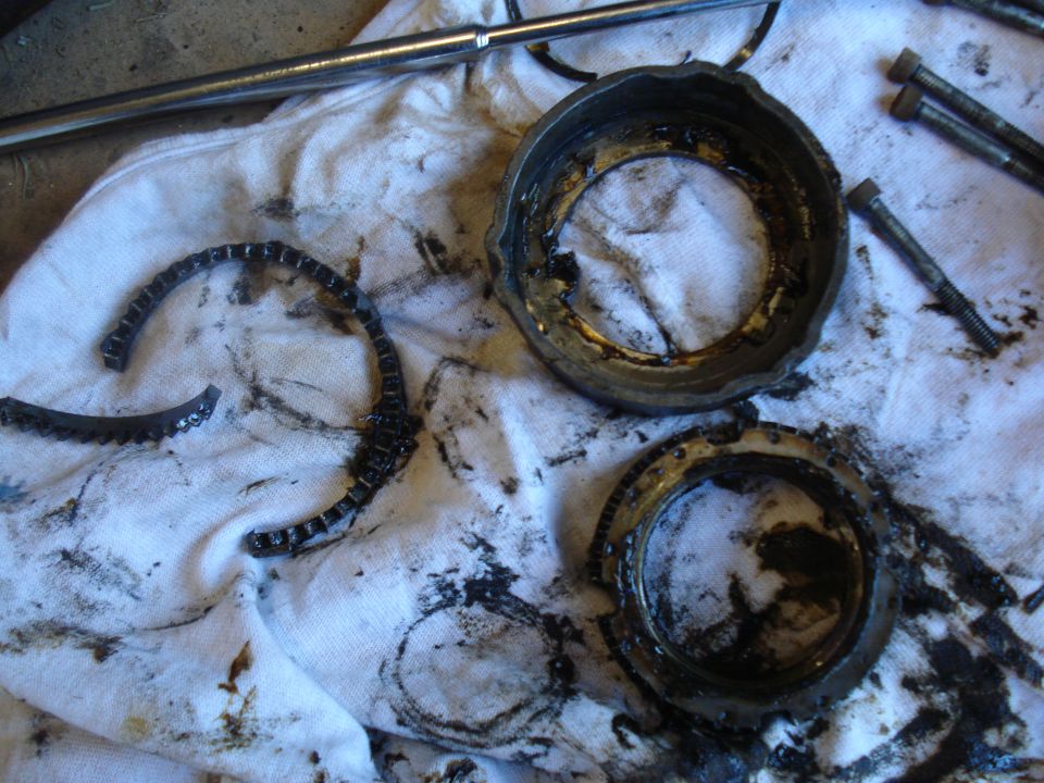 Broken metal ring and two circular metal housings covered in grease on a white cloth