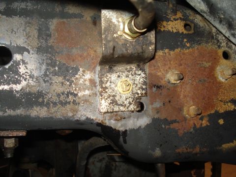 1989 Ford F-250 - Rusted truck frame shows a bracket attached to the chassis, holding a brake line.