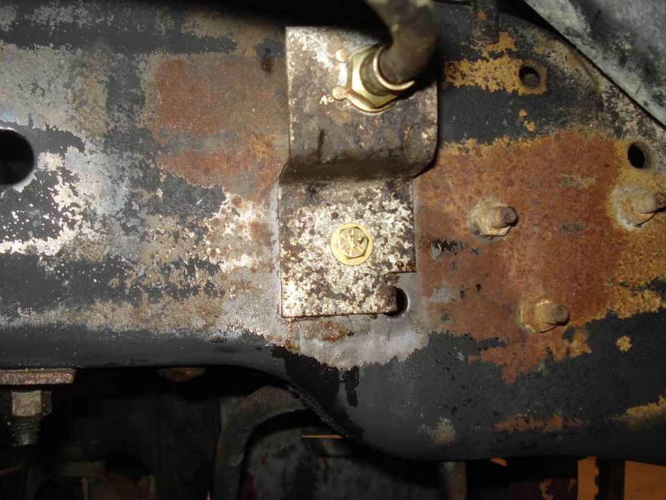 Close-up of a rusted truck frame with a metal bracket holding a brake line