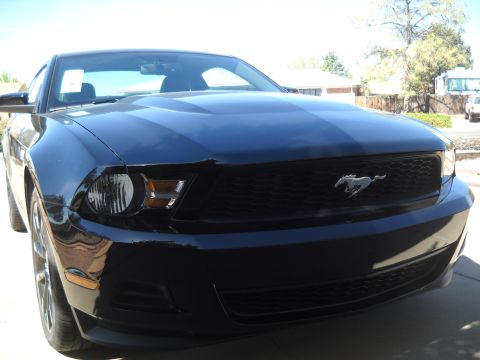 2012 Ford Mustang - A black Ford Mustang is shown from the front, its distinctive grille and headlights.