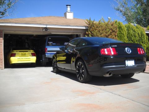 2012 Ford Mustang - Two Ford Mustangs and a van are parked in a driveway with an open garage.