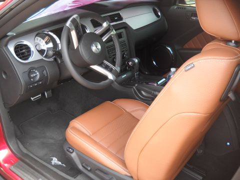 2012 Ford Mustang - The interior of a 2012 Ford Mustang features brown leather seats and a modern dashboard with chrome accents.