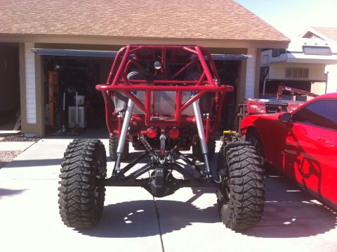 2009 Suzuki Samurai - Custom off-road buggy rear axle and suspension components are visible, alongside a red car.
