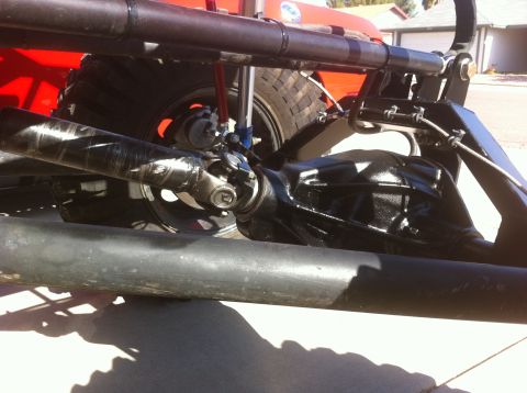 Suzuki Samurai - This photo shows the rear axle assembly and driveshaft of a vehicle, with visible suspension components and a large tire.
