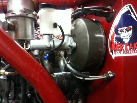 Suzuki Samurai - Close-up of a vehicle's brake master cylinder and booster assembly, with a sticker on the red body panel.