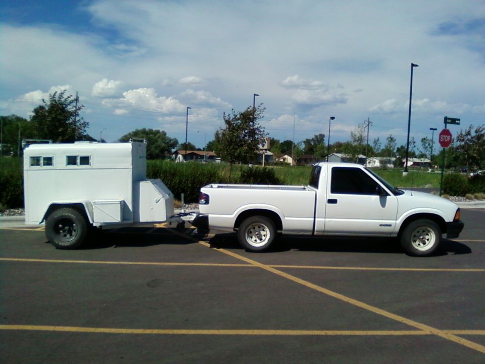White pickup truck towing a white enclosed trailer, side view