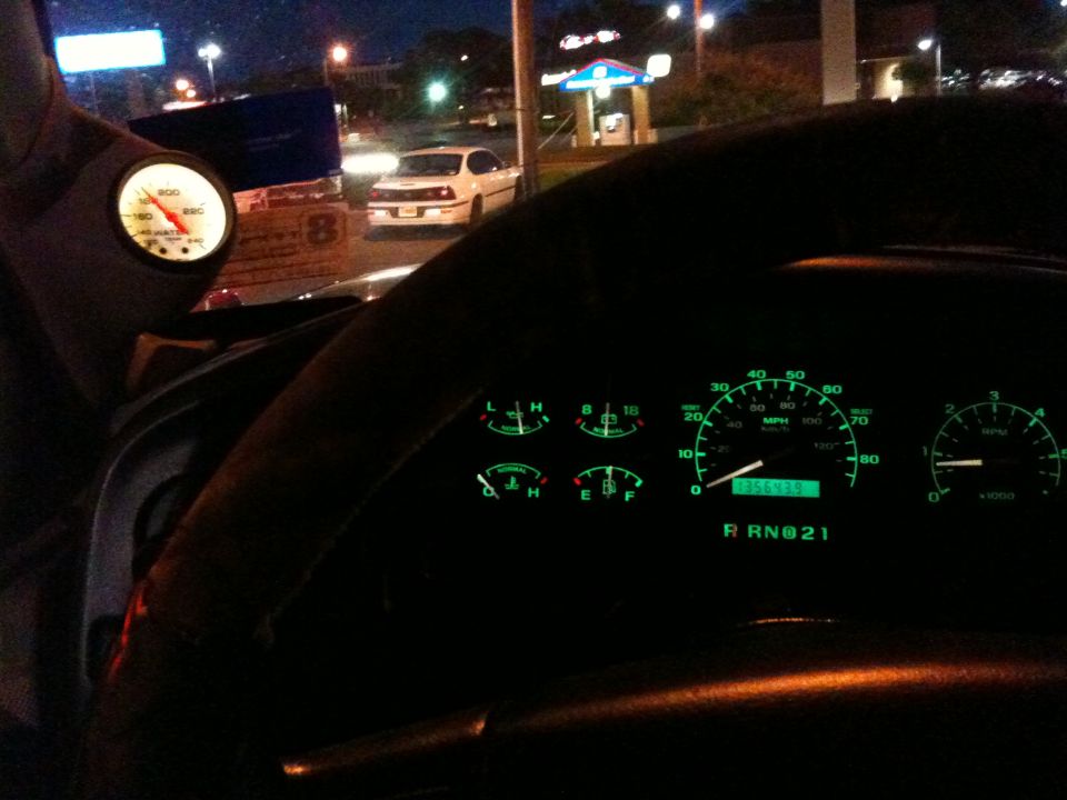 Interior view of a dashboard with illuminated gauges and a digital odometer reading 055575