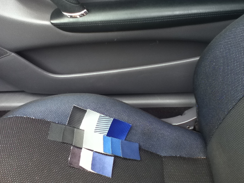 Fabric swatches laid out on a car seat, showing various shades of blue, grey, and black