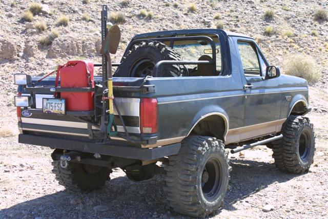 Gray lifted Ford Bronco with rear tire carrier and off-road mods in desert