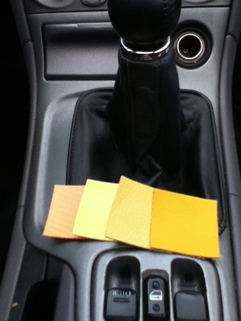 2006 Ford E350 - Four yellow-toned fabric swatches are placed on the center console of a vehicle, next to the shift boot.