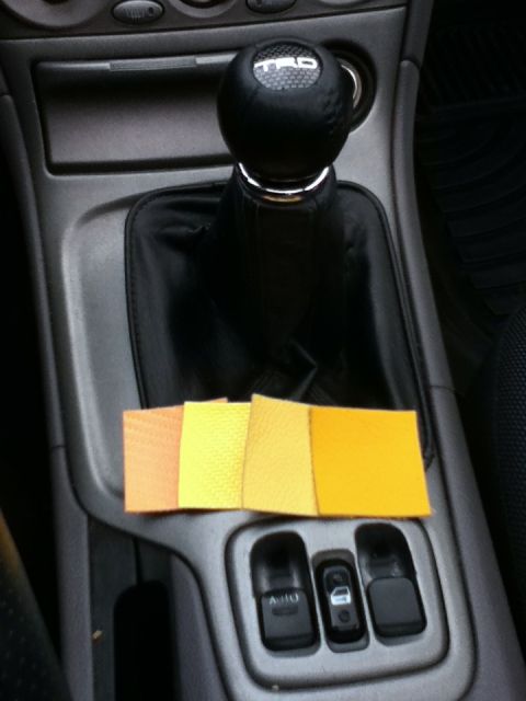 2006 Ford E350 - Swatches of yellow fabric are laid out on the center console of a car, next to the gear shifter.