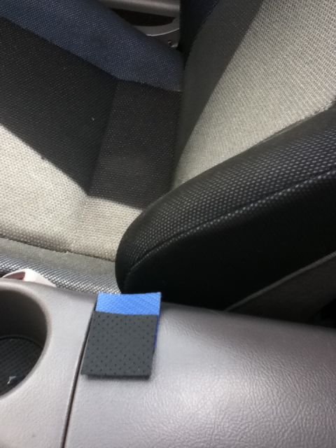 2006 Ford E350 - Close-up inside a car cabin looking across the gray plastic center console with a round cup holder toward black perforated-cloth and tan/gr…