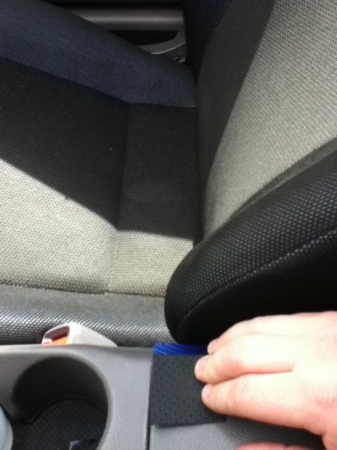 2006 Ford E350 - A hand touches the textured panel of a car's center console, near the seats.