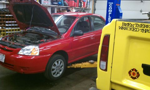 1999 Ford Expedition - A red sedan is on a car lift in a garage, with a yellow vehicle to its right.