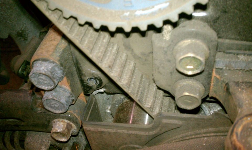 Close-up of a timing belt and pulley system with bolts
