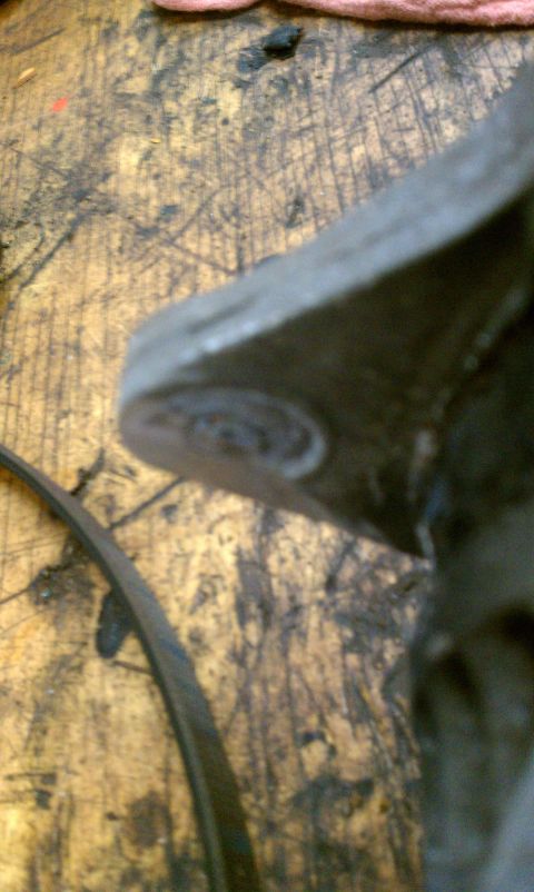 1999 Ford Expedition - A close-up view of an engine component and a belt, resting on a worn wooden workbench.