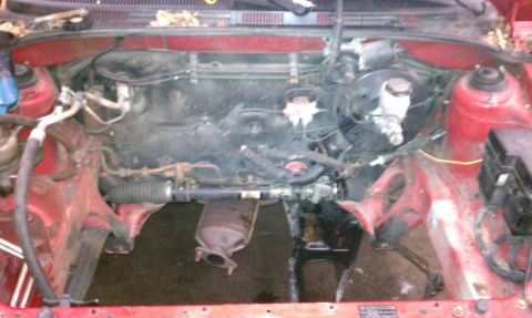 1999 Ford Expedition - The engine bay of a red vehicle is shown with the engine partially disassembled and components removed.