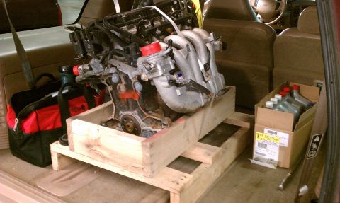 1999 Ford Expedition - Engine being transported in the cargo area of a vehicle, alongside tools and fluids.