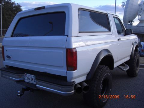 1996 Ford Bronco - Rear view of a white 1996 Ford Bronco showing its dual exhaust pipes and aftermarket wheels.