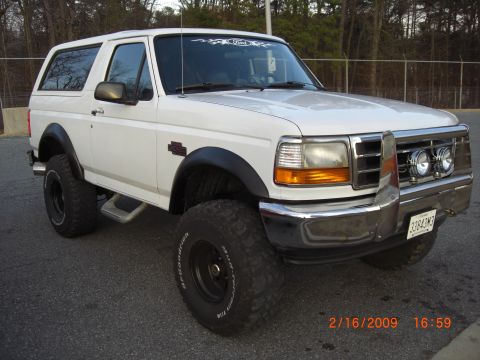 1996 Ford Bronco - This white Ford Bronco, likely from the early to mid-1990s, is equipped for off-road use with large tires and a protective front bumper.