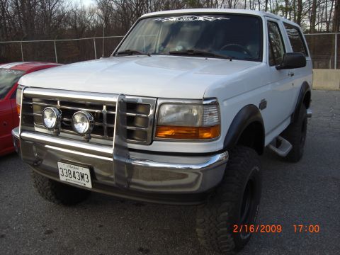 1996 Ford Bronco - White 1996 Ford Bronco with a chrome grille guard and auxiliary lights is parked outdoors.