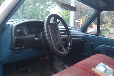 1996 Ford Bronco - Interior of a truck cab, showing the dashboard, steering wheel, and a red bench seat.