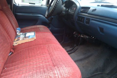 1996 Ford Bronco - Interior view of a truck's bench seat and dashboard, showing a book and a can on the seat.