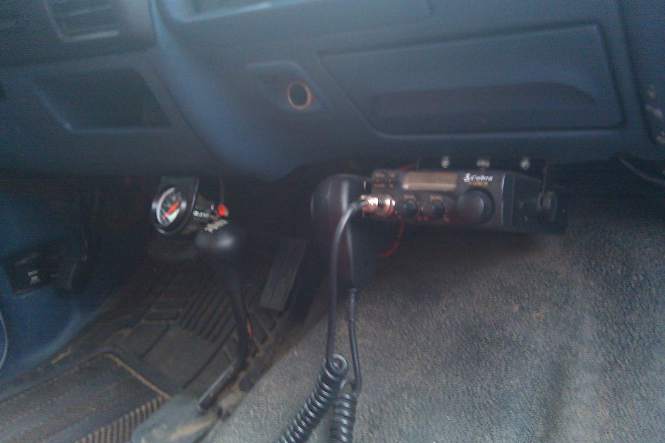 Vehicle interior showing a Cobra CB radio and a gauge mounted near the gear shifter