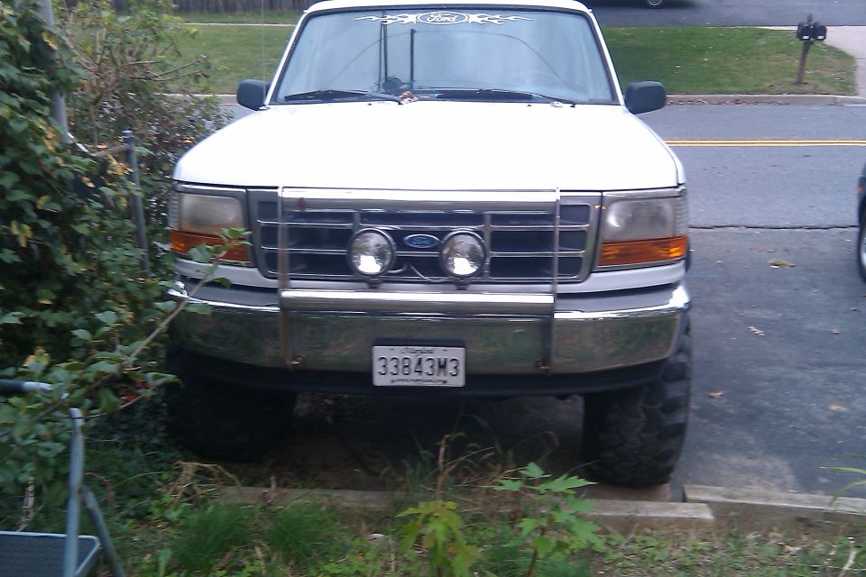 White Ford F-150 truck with a chrome bull bar and fog lights. License plate reads 33843M3