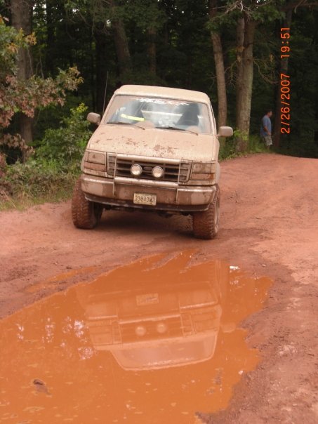 1996 Ford Bronco - Muddy 1996 Ford Bronco on a dirt road, reflected in a puddle.
