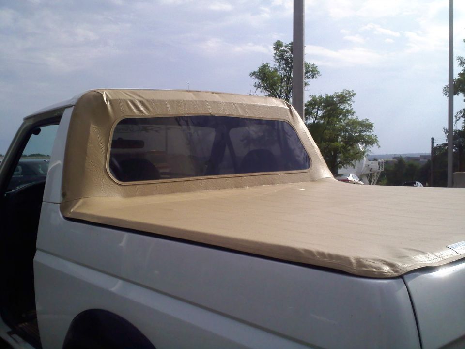 White Ford truck with tan soft top and beige tonneau cover over the bed