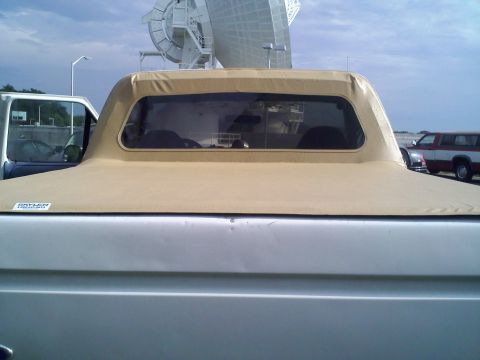 1996 Ford Bronco - This Bronco has a soft top covering the bed, and a large satellite dish is visible in the background.