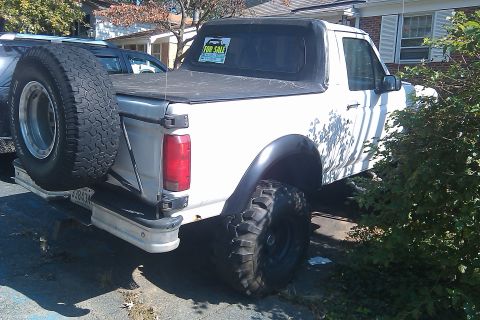 1996 Ford Bronco - Rear view of a 1996 Ford Bronco with a soft top and a spare tire on the bumper.
