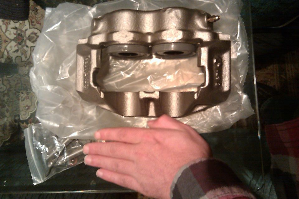 Bronze brake caliper in plastic packaging, held by a hand